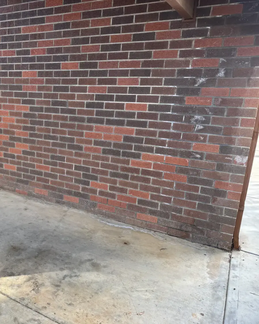 After: Clean concrete floor beside the brick wall