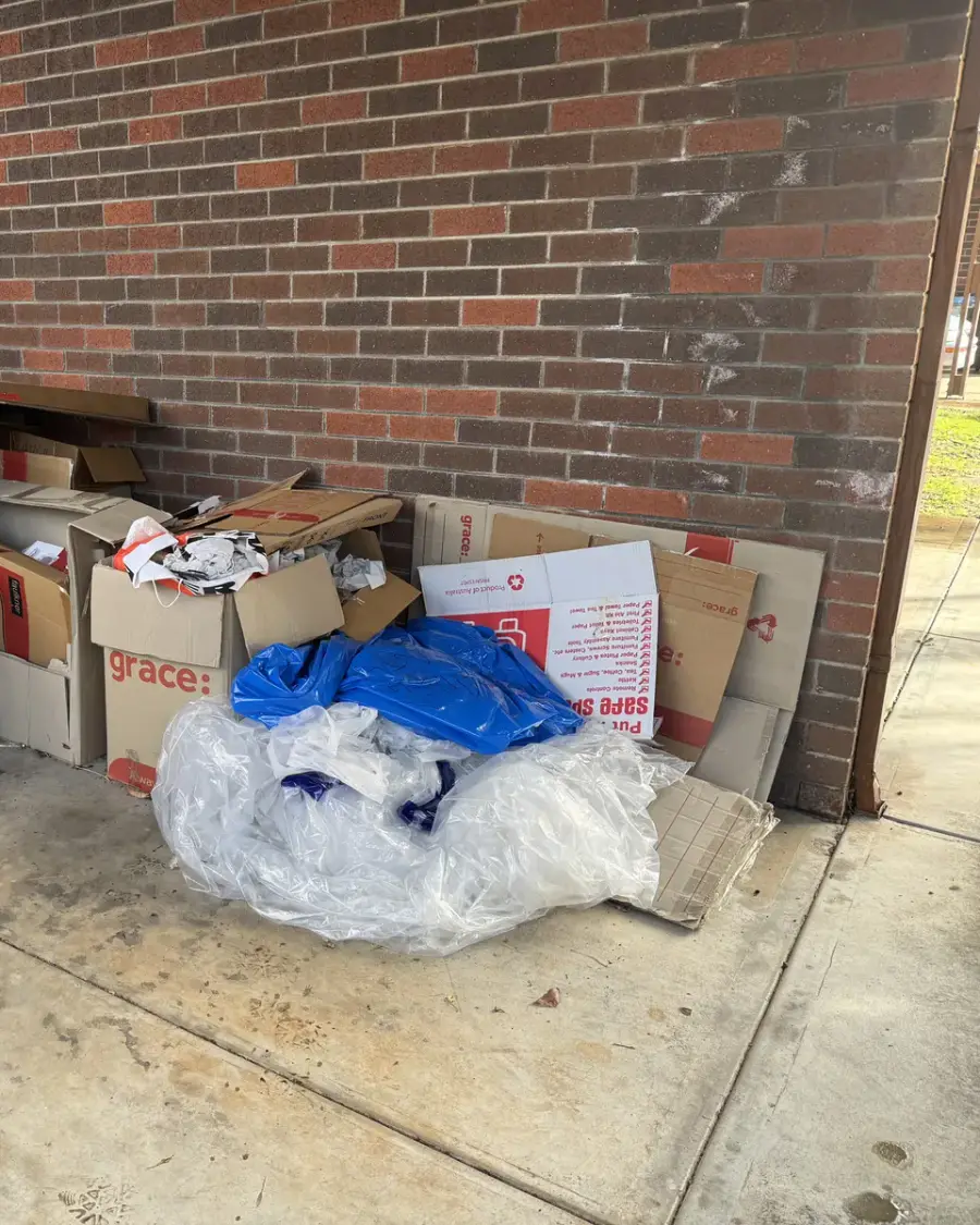 Before: Moving boxes and plastic packaging stacked against a brick wall