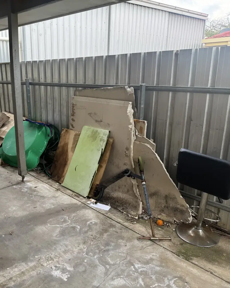 Before: Mattress, timber boards and bulky rubbish piled in a carport