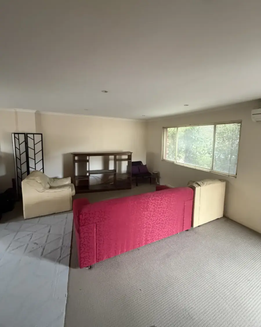 Before: Lounge room with a red couch, cream armchairs and a TV cabinet