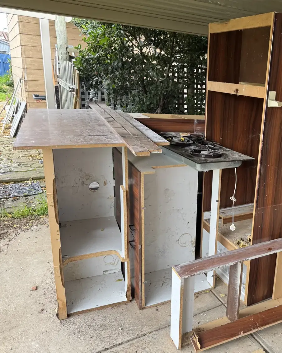 Before: Pulled-out kitchen cabinets and benchtop with a cooktop on a patio