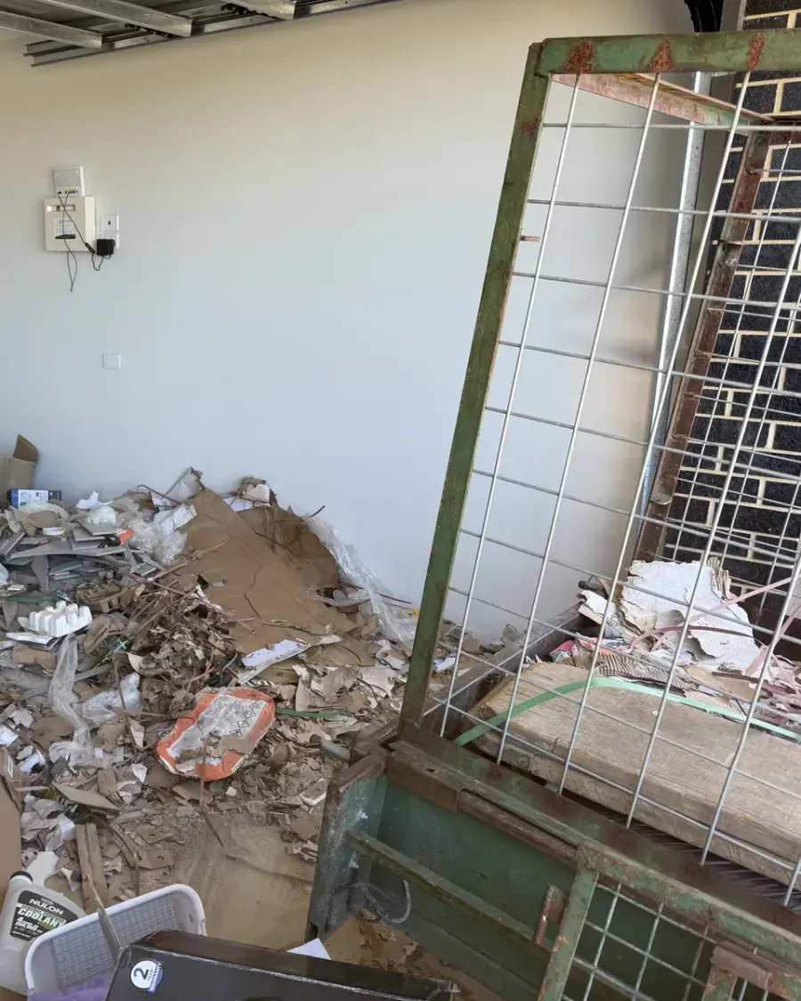 Before: Broken plaster, cardboard and renovation debris piled against a wall
