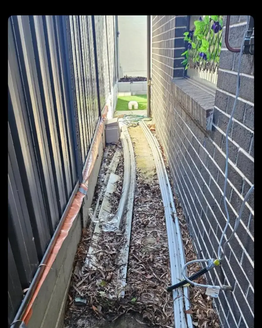 Before: Old downpipe and leaf litter along a narrow side path