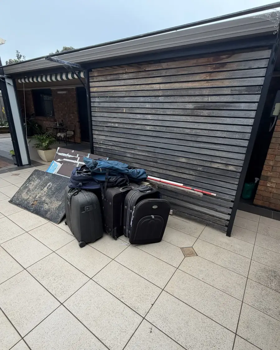 Before: Suitcases and household items in a paved courtyard
