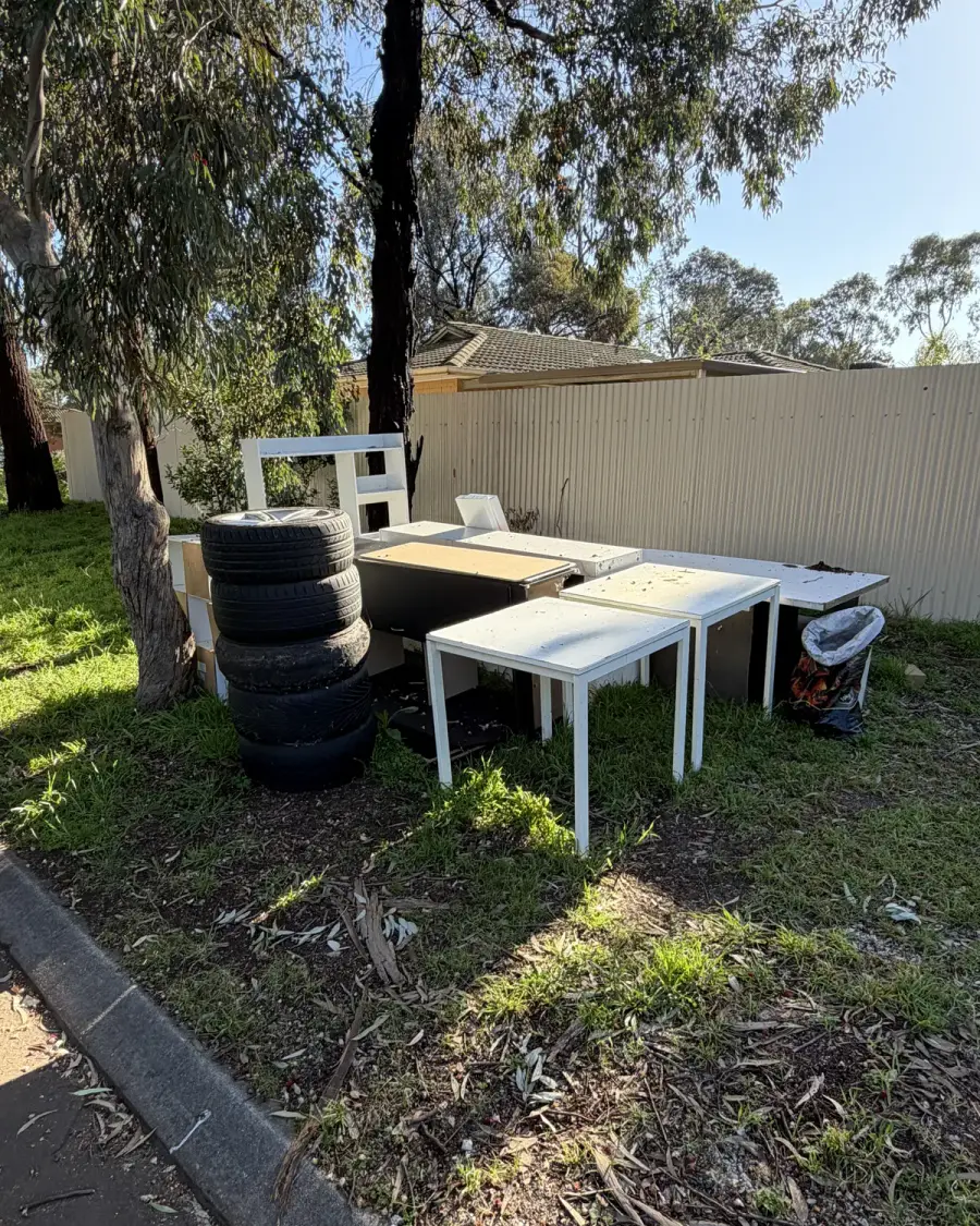 Before: Stack of old tyres, desks and tables on the grass
